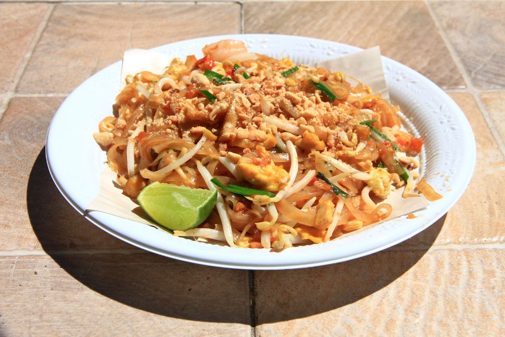 A plate of Pad Thai with fresh lime, peanuts, and stir-fried noodles. One of the reasons to visit Thailand, known for its world-renowned cuisine, making Thailand a great holiday destination.