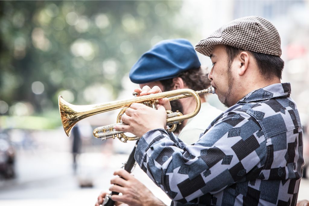 Two musicians playing brass instruments in a public space, showcasing Singapore’s vibrant culture. However, performing without a license can violate the city’s rules, an important law in Singapore to know before engaging in street entertainment.