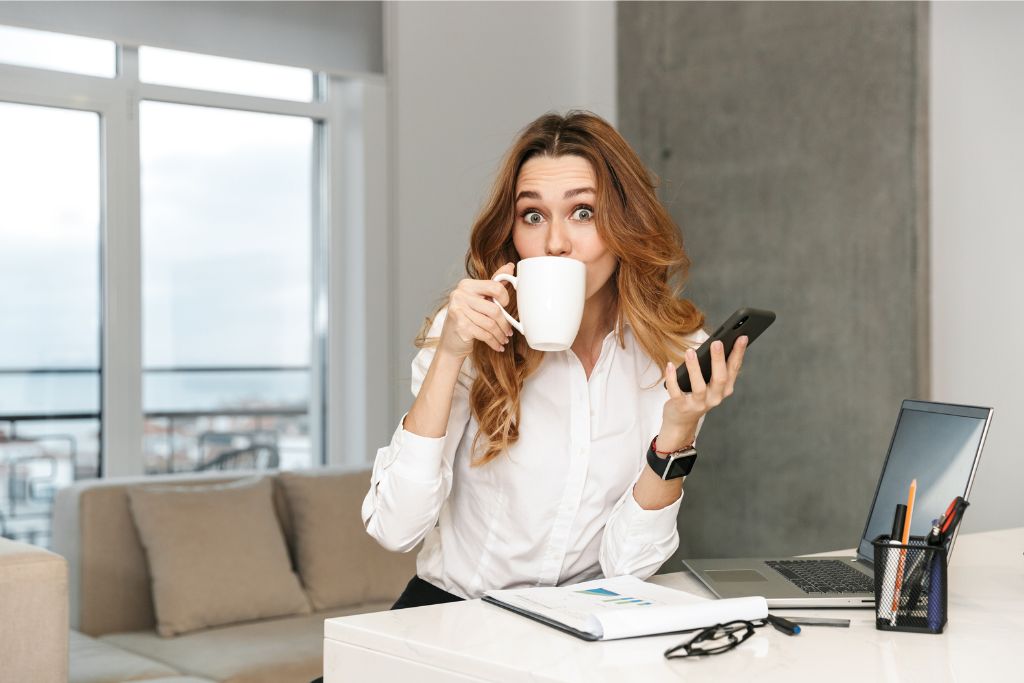 A woman sipping her coffee at a modern workspace, multitasking between her phone and notes. While Singapore thrives on productivity, unspoken rules about noise and public behavior remind visitors to be mindful of their surroundings.