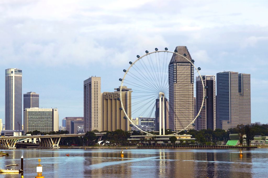  scenic view of the Singapore Flyer with modern skyscrapers in the background and a reflection in the water. Highlights Singapore’s cityscape and architectural beauty, a must-visit winter destination.