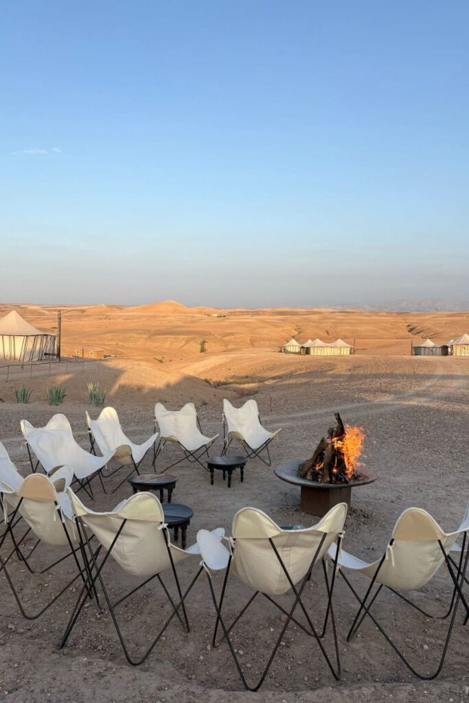 A group of white chairs arranged around a campfire in a desert glamping setup, evoking the freedom and peace of solo travel experiences and the journey of gaining parental approval to explore remote, safe destinations.