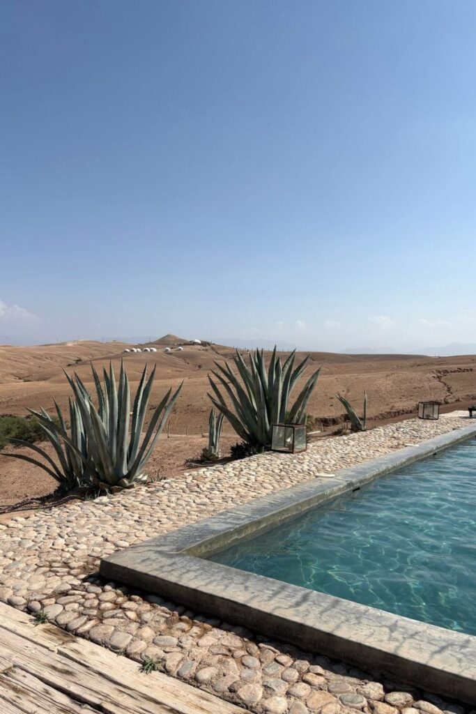 Desert resort scene with a turquoise pool and agave plants, perfect for highlighting peaceful destinations when exploring where to travel alone and how to convince your parents to let you go on vacation safely.
