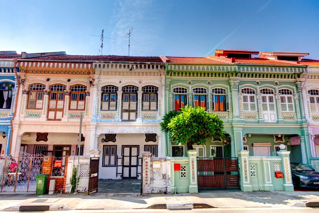 A vibrant row of pastel Peranakan shophouses with intricate window detailing and red-tiled roofs under a clear sky in Katong, Singapore. Visiting these heritage homes is one of the more unique things to do in Singapore and offers a glimpse into the city’s multicultural architecture.