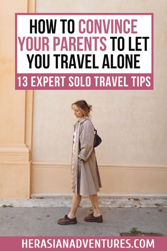 Woman in a neutral trench coat walks solo by a beige wall with text overlay: “How to convince your parents to let you travel alone – 13 expert solo travel tips,” targeting tips for solo female travelers and building trust for solo trips.