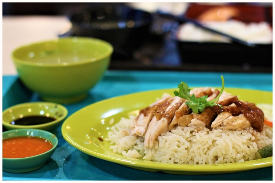 A plate of Hainanese chicken rice, a popular dish found in hawker centers in Singapore. This image highlights one of Singapore's best hawker stalls, featuring a must-try Singaporean dish