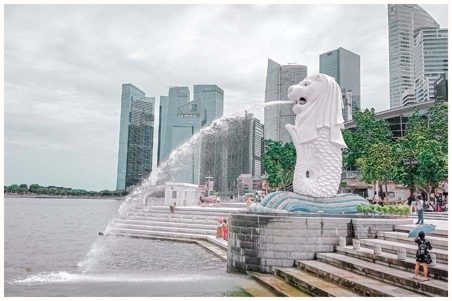 The Merlion statue with a water fountain in Singapore's Marina Bay, highlighting Singapore travel time from various locations worldwide.