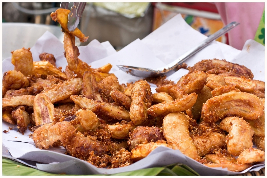 pile of freshly fried banana fritters at a hawker stall. This image captures the delicious street food to eat in Singapore, emphasizing the best affordable snacks found at Singapore's hawker centers.