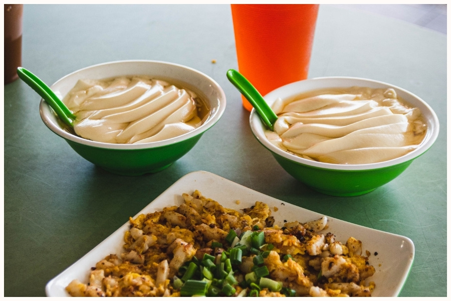 Bowls of tofu pudding and a plate of carrot cake served with a drink. This scene showcases the variety of hawker breakfast options available in Singapore, perfect for those looking for budget food in Singapore.