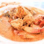 A plate of rich, spicy chili crab, a signature Singaporean dish, served at a hawker center. This image highlights the best hawker food in Singapore, a must-try for anyone exploring what to eat in Singapore.