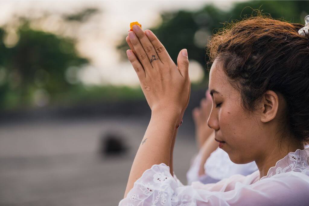 A woman with hands clasped in prayer at Batu Caves temple in Kuala Lumpur, Malaysia. Batu Caves, a significant Hindu temple, draws both tourists and worshippers from around the world, offering spiritual and cultural experiences as part of Batu Cave tours.