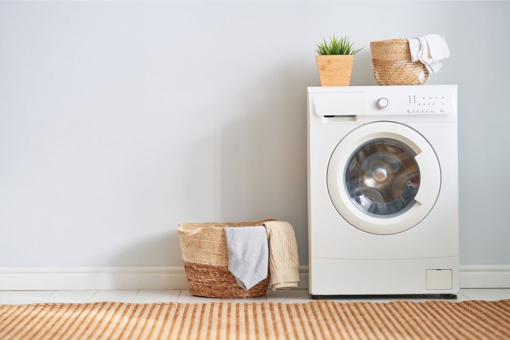 A laundry setup with a basket and a washing machine, representing how washing clothes during a trip can help avoid overpacking.