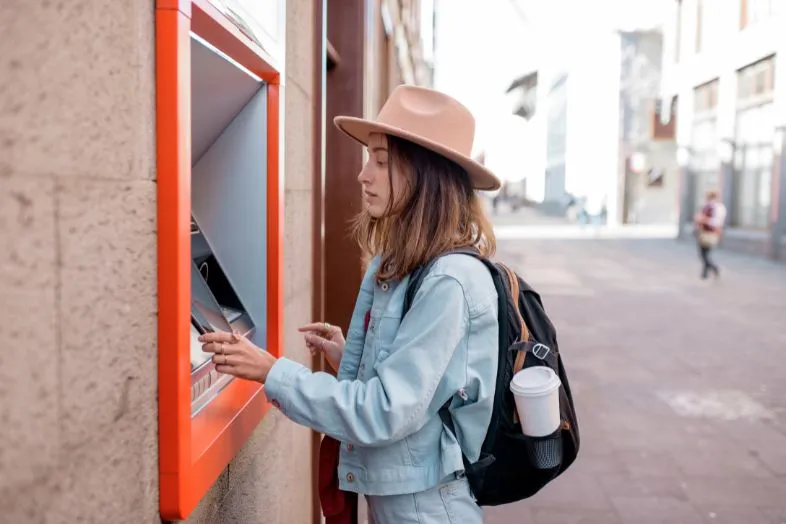 An essential part of managing money while traveling Southeast Asia is using ATMs for cash withdrawals. This photo shows a traveler withdrawing local currency, a practical tip to avoid high airport exchange fees and ensure access to funds in rural areas.