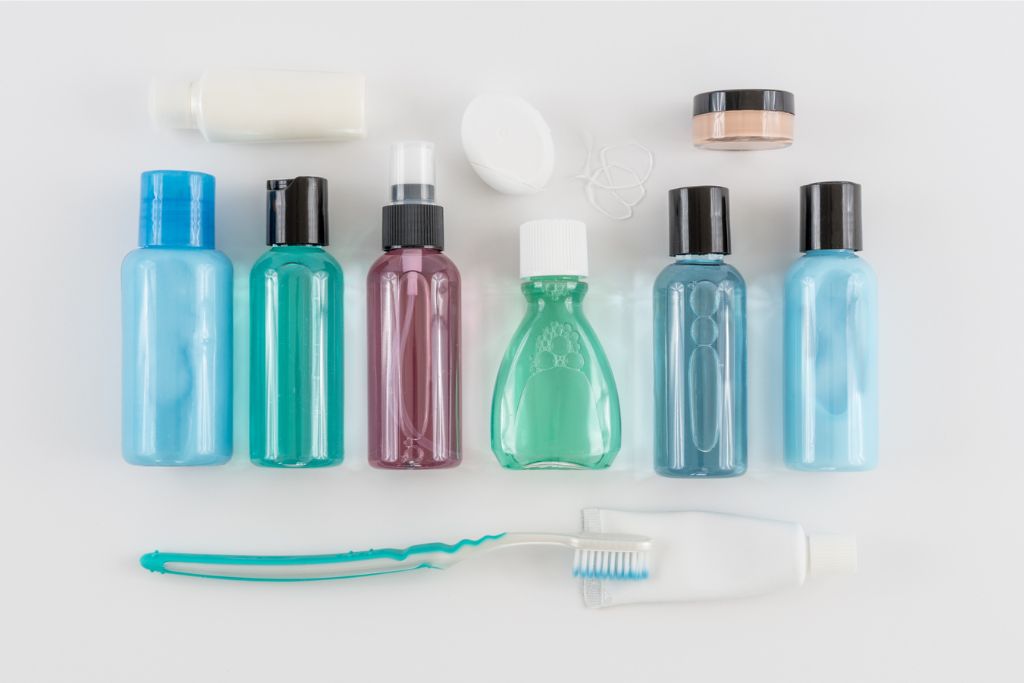 Travel-sized toiletries and personal care items arranged on a flat surface. This image showcases essential packing tips for girls, offering advice on how to avoid overpacking by limiting liquids to travel-sized containers, preventing the need to over pack.