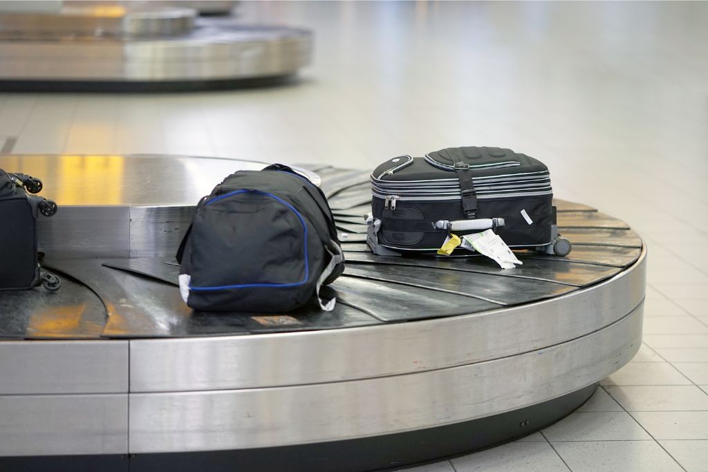 Luggage on a carousel in the baggage claim area. A practical illustration for first time airplane travelers, explaining what to expect when retrieving luggage after a flight.