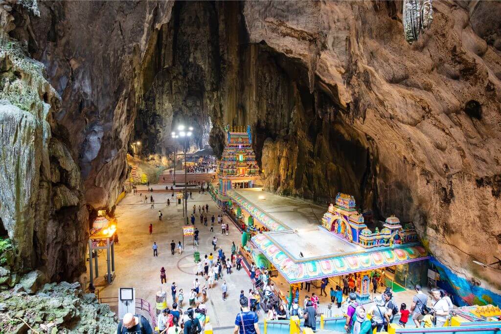 A view inside the Temple Cave at Batu Caves, showcasing the grand Hindu temple structures and visitors exploring the area. Batu Caves, one of Malaysia’s top attractions, offers a unique blend of cultural and natural beauty for tourists on Batu Cave tours.