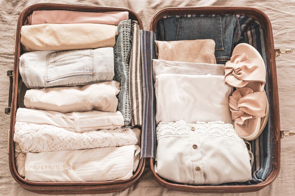 A perfectly packed suitcase with clothes neatly folded and shoes placed carefully, providing a visual on how to stop overpacking by organizing items in a structured way. This image offers practical advice on how to avoid overpacking for a vacation