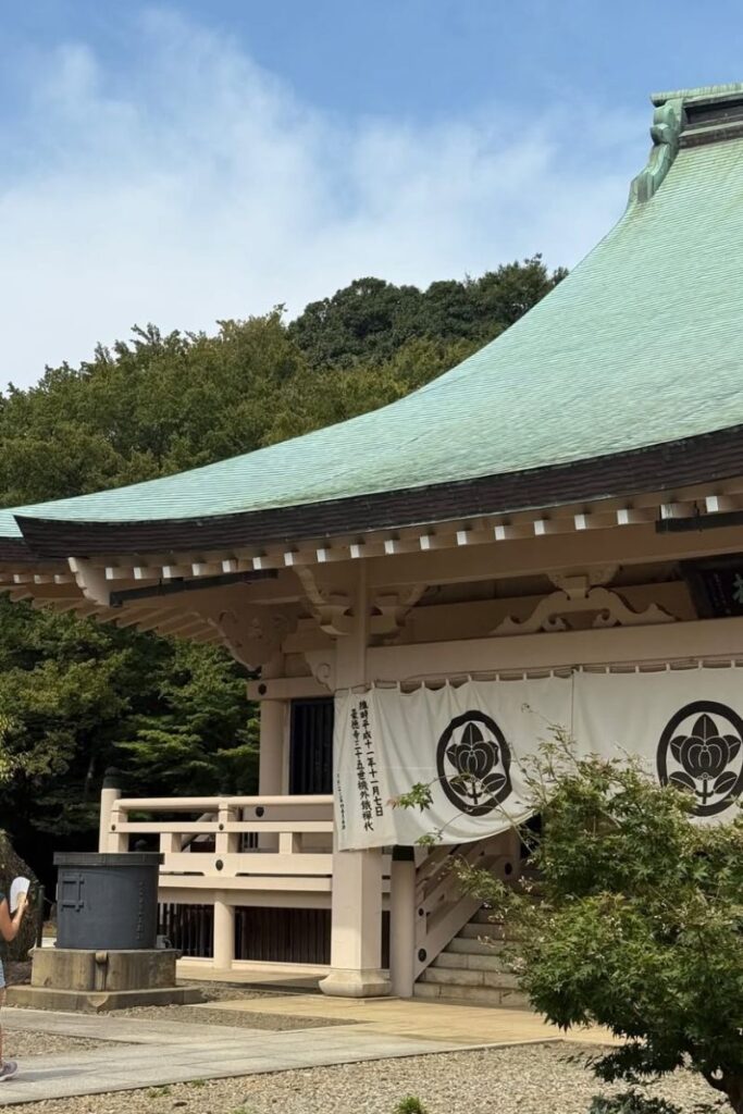 A serene temple with a pale green-tiled roof surrounded by lush trees and blue sky. This peaceful shrine is a cultural highlight of autumn in Asia and a calming stop for travelers exploring Asia fall destinations.