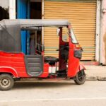 A red tuk tuk parked on the street in Sri Lanka, showcasing the Sri Lanka tuk tuk aesthetic and a common way to travel around the island. Renting a tuk tuk in Sri Lanka is a popular way to explore.