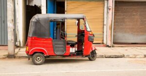 A red tuk tuk parked on the street in Sri Lanka, showcasing the Sri Lanka tuk tuk aesthetic and a common way to travel around the island. Renting a tuk tuk in Sri Lanka is a popular way to explore.