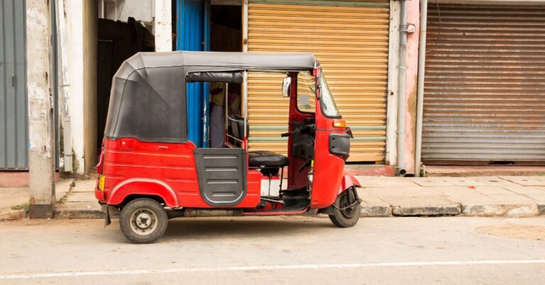 A red tuk tuk parked on the street in Sri Lanka, showcasing the Sri Lanka tuk tuk aesthetic and a common way to travel around the island. Renting a tuk tuk in Sri Lanka is a popular way to explore.