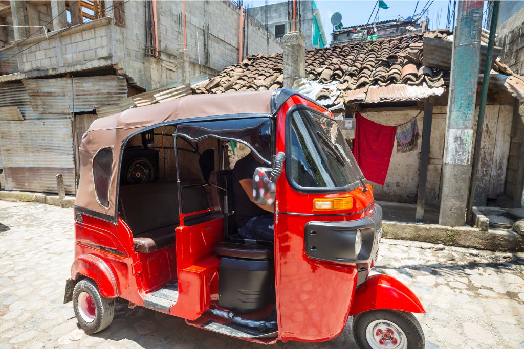 A vibrant red tuk tuk parked on a cobbled street in a Sri Lankan village. Tuk tuk rentals in Sri Lanka offer a unique and immersive travel experience, making it one of the best ways to get around.