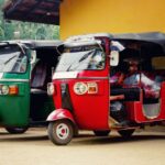 : A red and green tuk tuk parked side by side near a vibrant yellow wall in Sri Lanka, showcasing the island's tuk tuk culture. Renting a tuk tuk in Sri Lanka is a budget-friendly and iconic way to explore the country.