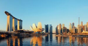 A golden sunset reflects on the water in front of Marina Bay Sands and the Singapore skyline. This iconic view is one of the top reasons to visit Singapore, showcasing why Singapore is worth visiting for its stunning modern architecture and waterfront scenery, making it a memorable holiday destination.