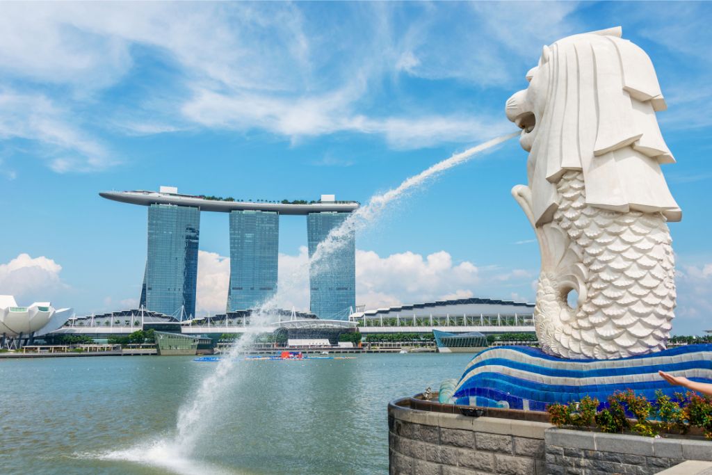 The famous Merlion statue in Singapore, with Marina Bay Sands in the background. This symbol of the city offers a compelling reason to travel to Singapore and showcases why the city is worth visiting for its iconic landmarks.