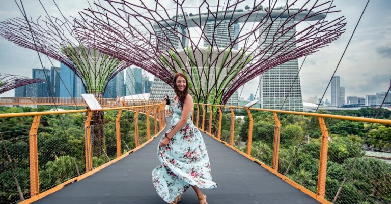 A woman in a floral dress twirls joyfully on the OCBC Skyway, surrounded by Singapore’s iconic Supertrees with Marina Bay Sands in the background. This picturesque scene is one of the top reasons to visit Singapore and helps answer the question: is Singapore worth visiting for travelers seeking stunning views and unique experiences.