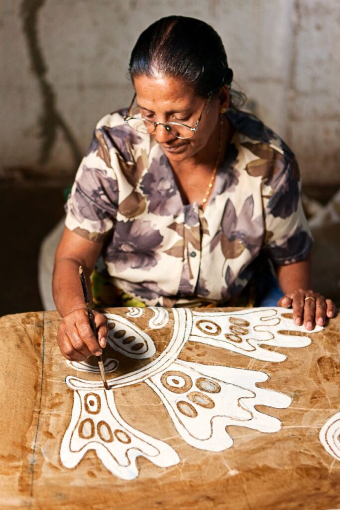 A Sri Lankan artisan meticulously painting batik patterns on fabric, showcasing traditional craftsmanship. Ideal as a unique souvenir from Sri Lanka, reflecting the island’s rich textile artistry.