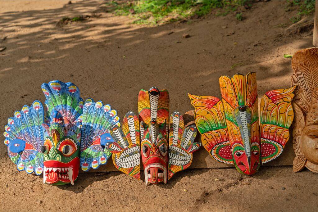 Handcrafted wooden masks in vibrant colors and intricate designs displayed on the ground, showcasing traditional Sri Lankan culture. These masks are unique souvenirs from Sri Lanka and are popular for home decor.