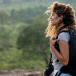 A woman wearing lightweight adventure clothing with a backpack and camera enjoys a hike through Sri Lanka’s lush landscapes. Perfect for packing tips for Sri Lanka and clothing for adventure travel.