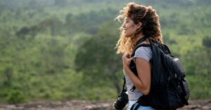 A woman wearing lightweight adventure clothing with a backpack and camera enjoys a hike through Sri Lanka’s lush landscapes. Perfect for packing tips for Sri Lanka and clothing for adventure travel.