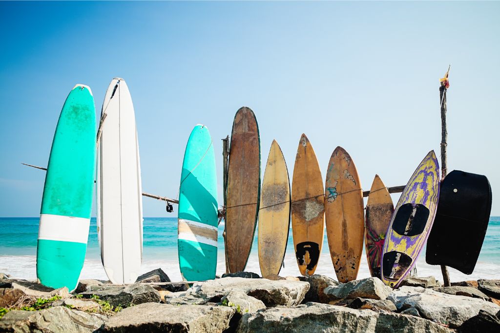 Colorful surfboards lined up against rocks by the ocean, showing why the best time to go to Sri Lanka includes enjoying surf-friendly weather.