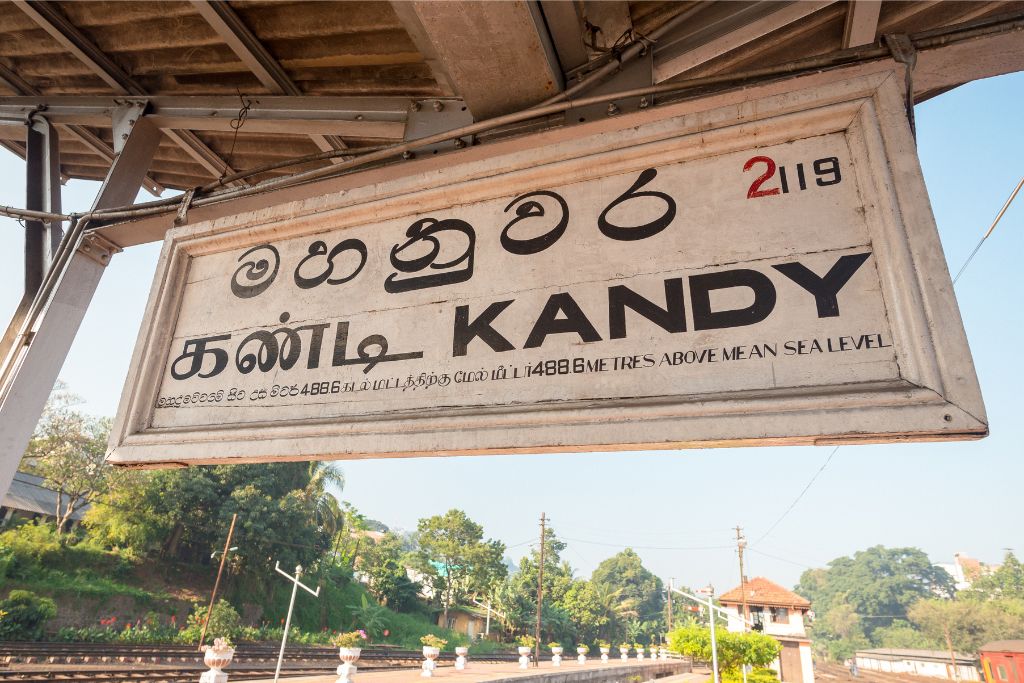 Railway sign for Kandy station with text in Sinhala, Tamil, and English, marking a cultural highlight during the best time to travel to Sri Lanka.