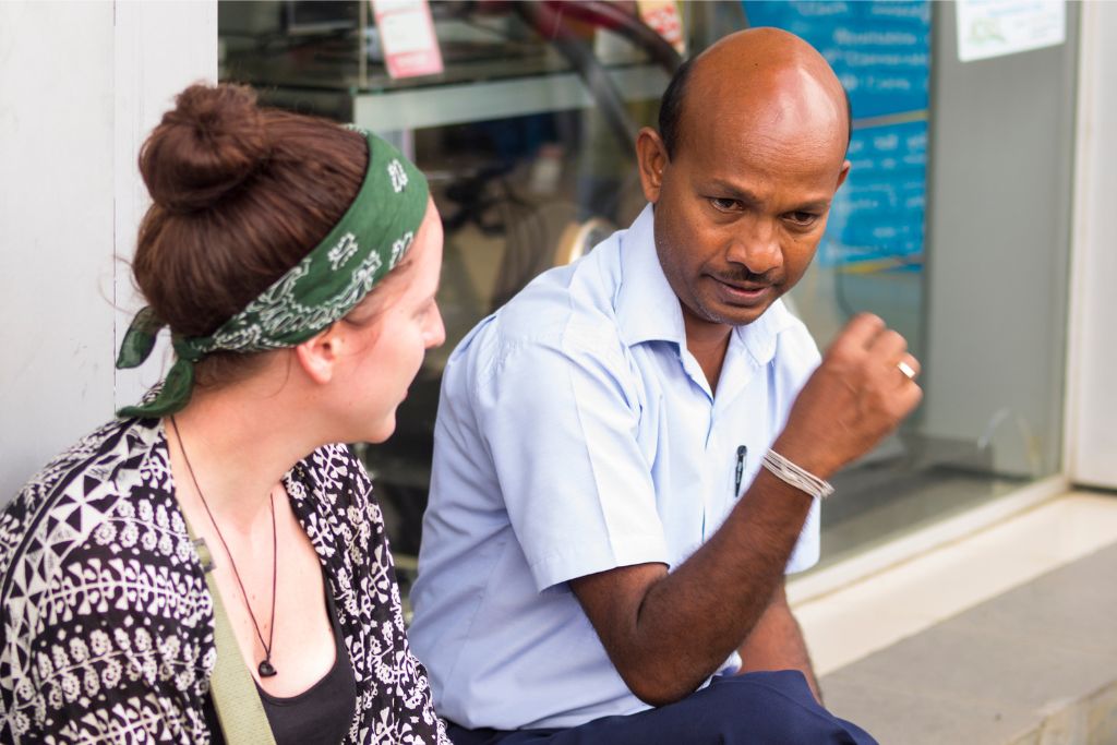 A traveler enjoys a conversation with a local, showcasing cultural connection and comfortable travel clothing. A must-know for dress code in Sri Lanka and what to bring on vacation.