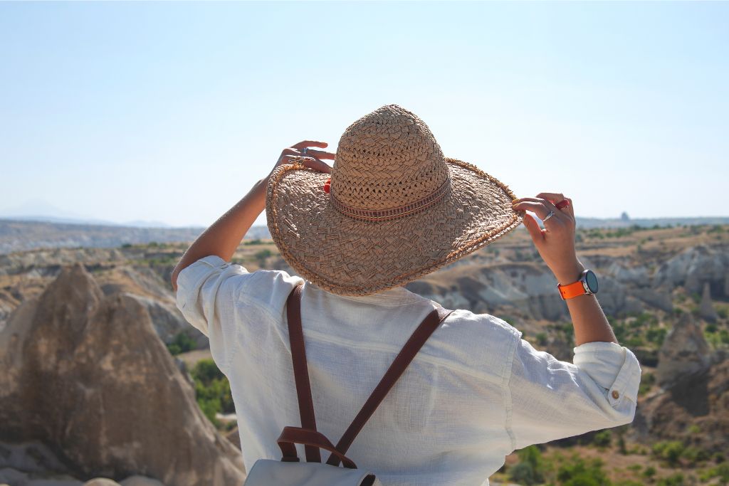 A traveler wearing a straw hat enjoys stunning views of Sri Lanka’s rocky terrain and bright skies. Perfect for tropical vacation outfit ideas and Sri Lanka summer packing list.