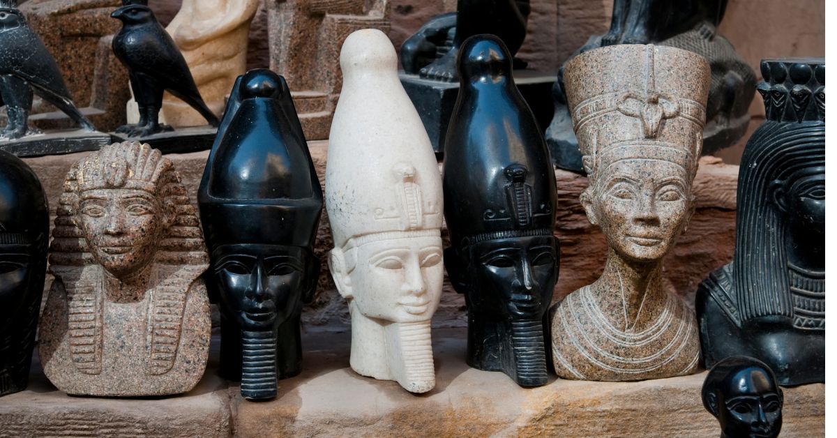 A display of Ancient Egypt souvenir statues, including pharaohs and deities, in a variety of materials like black stone and alabaster, found in the vibrant Bazaar Khan el Khalili, Cairo, Egypt.