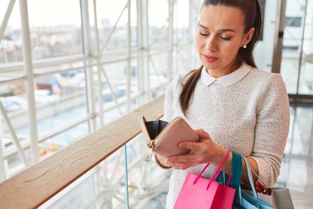 A woman holding a wallet while shopping, considering money travel tips and strategies for how to bargain like a pro when traveling.