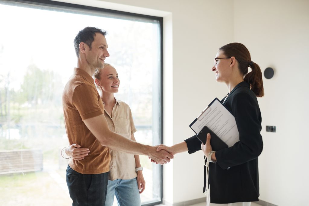 A couple shaking hands with a professional, illustrating negotiation techniques and the value of haggling tips for transactions during travel.