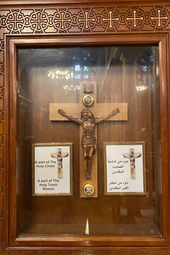 A wooden display case featuring a crucifix said to contain relics of the Holy Cross and Holy Tomb Stones, emphasizing the sacred Christian history preserved in Coptic Cairo.