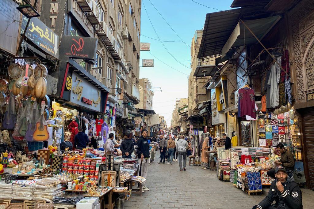 A bustling street in Khan el Khalili, Cairo, lined with shops offering textiles, handmade crafts, spices, and souvenirs, capturing the dynamic vibe of this iconic Egyptian bazaar.