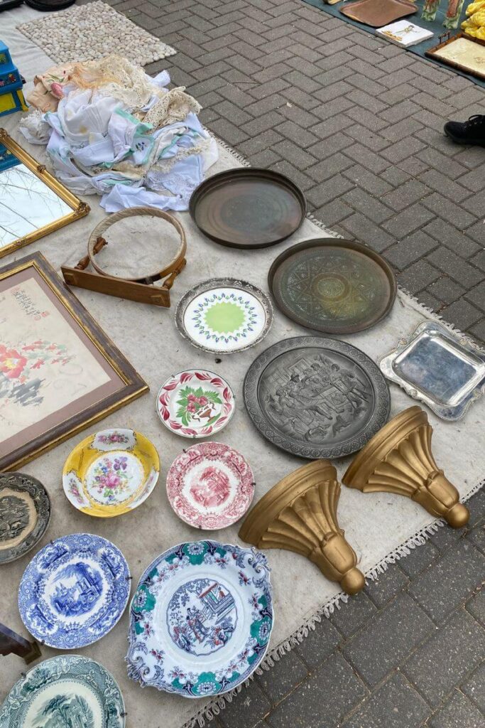 Colorful vintage plates, trays, and fabrics spread out on a market stall. Knowing how to haggle in Thailand or any tourist market can save you a fortune. Bargaining examples show that a polite negotiation can lead to big discounts.