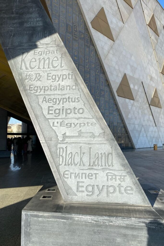 A close-up of a modern architectural feature at the Grand Egyptian Museum Cairo, with the word "Kemet" and "Egypt" inscribed in multiple languages—a fascinating element of the Grand Egyptian Museum inauguration.