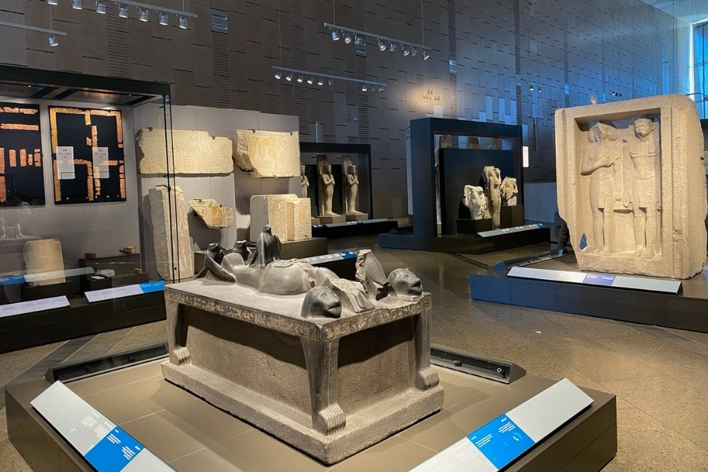 An exhibit inside the Grand Egyptian Museum shop, featuring artifacts, statues, and ancient relics displayed in a well-lit, modern setting, making it one of the best things to do at the Grand Egyptian Museum.