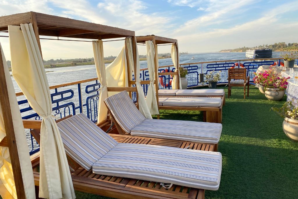 Poolside daybeds and cabanas aboard a Nile River cruise boat, set against scenic river views. This relaxing setting answers “is Egypt worth visiting” and highlights one of the top reasons to visit Egypt.
