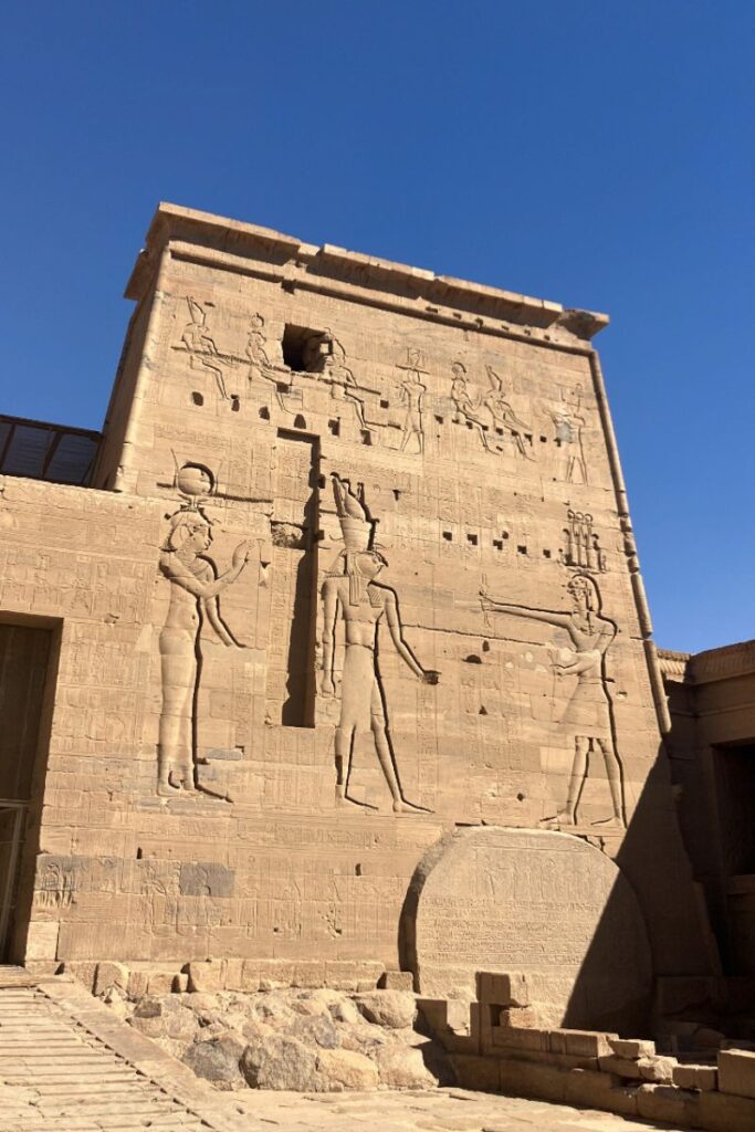 Towering facade of the Temple of Isis Egypt, part of the Philae Temple complex, featuring detailed carvings of Egyptian deities and showcasing ancient craftsmanship under a clear sky.