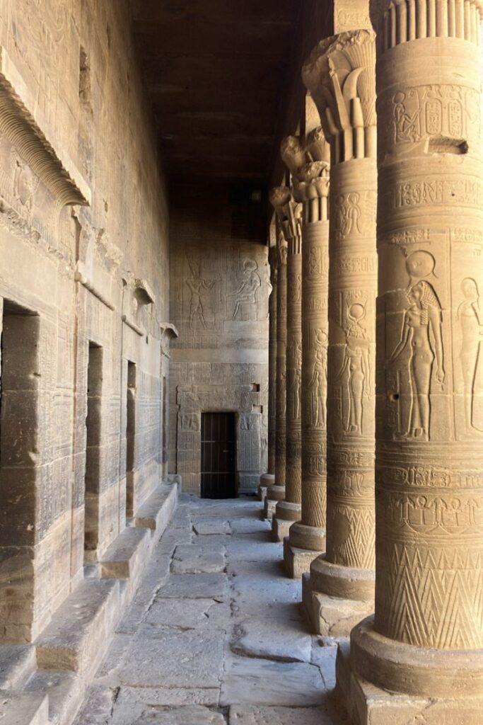 Interior corridor of the Temple of Isis at Philae, Egypt, lined with intricately decorated columns and hieroglyphs, illustrating the sacred and historic beauty of Philae temple Aswan.