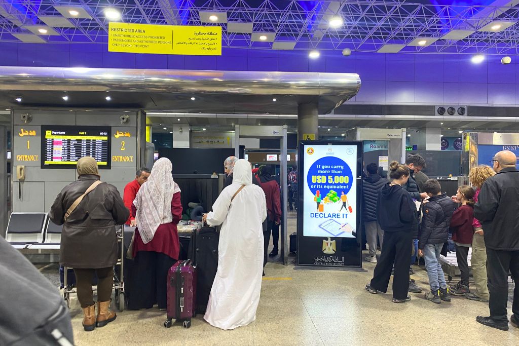 Travelers queuing at security in Cairo International Airport with signs in Arabic and English. Useful for travelers searching “Uber from Cairo airport,” wondering “does Uber operate in Egypt,” or comparing Egyptian taxi services to Uber or Careem.