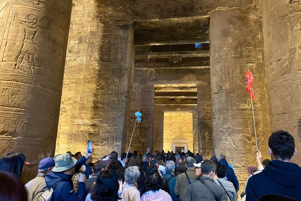 Crowds of tourists gather inside the Temple of Horus at Edfu, surrounded by towering columns covered in intricate hieroglyphs—an iconic experience for anyone wondering is it worth visiting the Temple of Horus at Edfu.